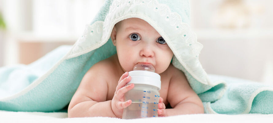 Baby mit Fläschchen unter einer Decke